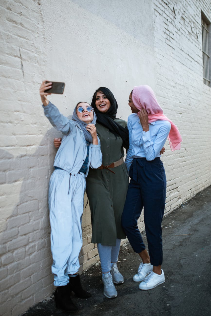 Charming young lady in trendy outfit smiling and posing for selfie on  blurred background of nature on sunny day.Stylish woman taking selfie in  country Stock Photo - Alamy